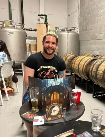 A person sitting behind a table with board games on it