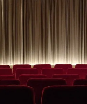 Image of a red seats in a movie theater with a brown curtain