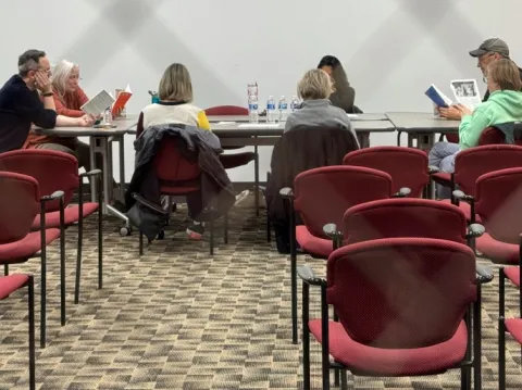 Image of people sitting around a long table reading