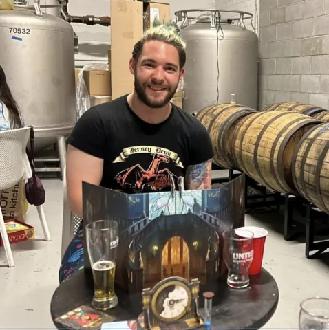 A person sitting behind a table with board games on it