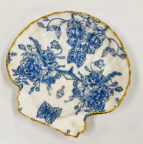Image of a seashell shaped dish with blue flowers on it and gold edging