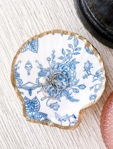Image of a seashell shaped dish with blue flowers on it and gold edging