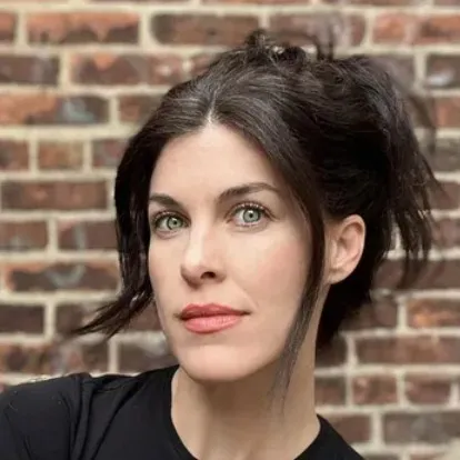 A headshot of the author with a brick background