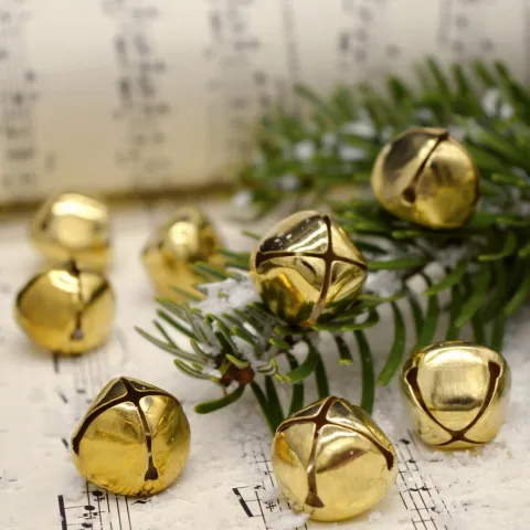 Gold jingle bells and a sprig of holly on sheet music