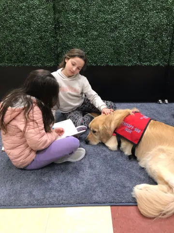 Girls read to a therapy dog.