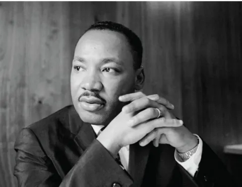 An image of Martin Luther King Jr. clasping his hands and looking off to the side