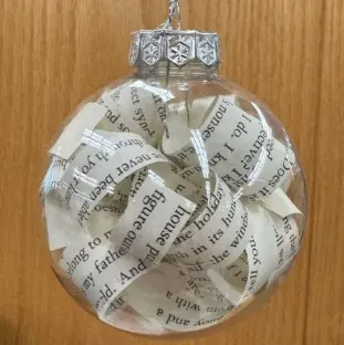 A round clear ornament filled with strips of book pages