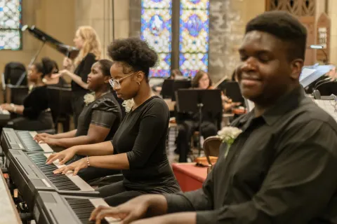 An image of people playing keyboards in a church