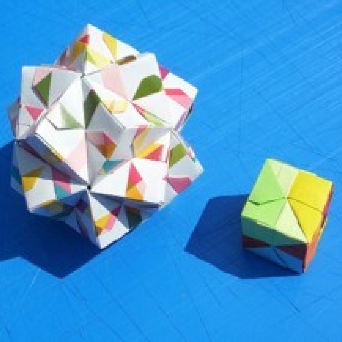 Image of a box made from folded paper and a 3D origami design on a blue background
