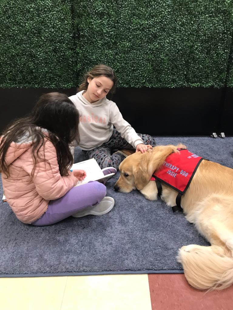 Girls reading to a therapy dog.