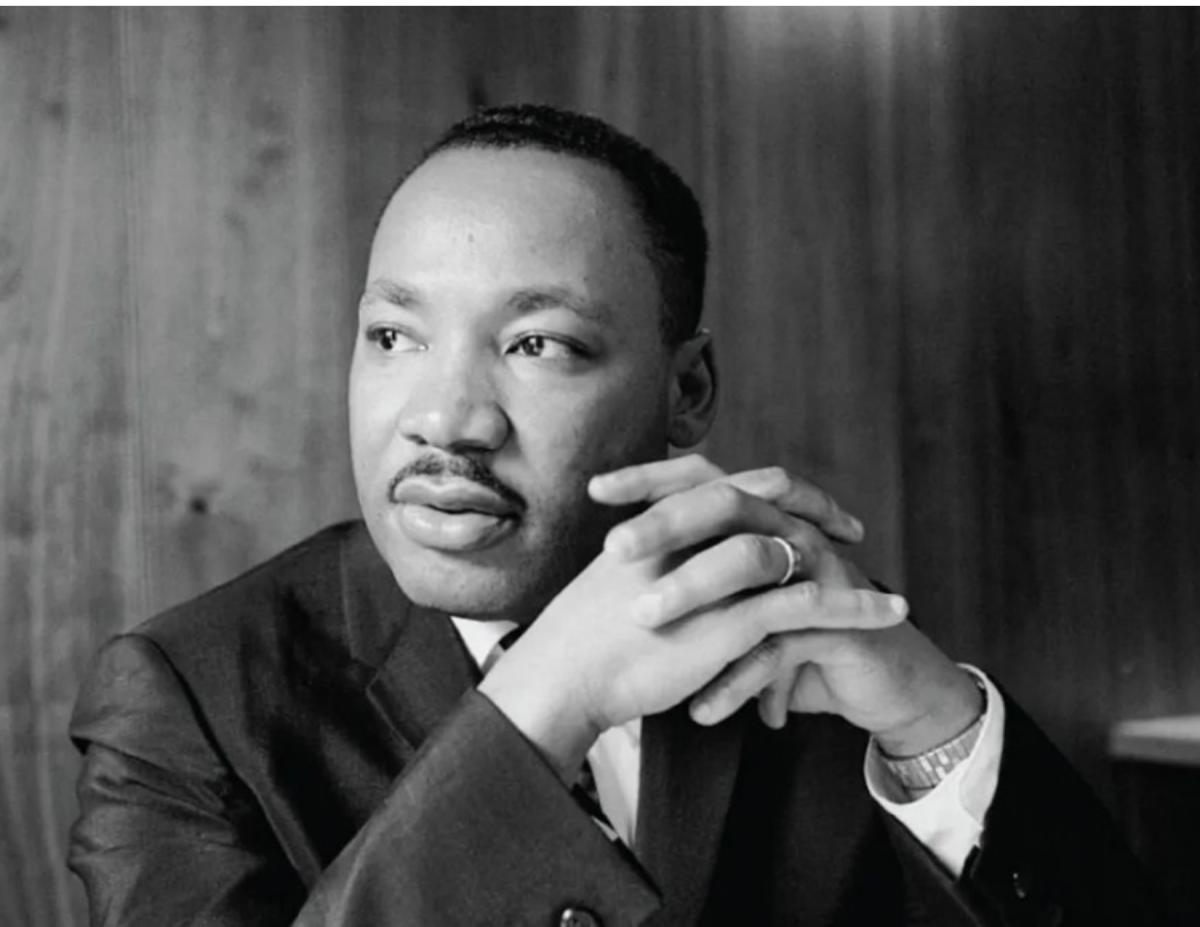 An image of Martin Luther King Jr. clasping his hands and looking off to the side